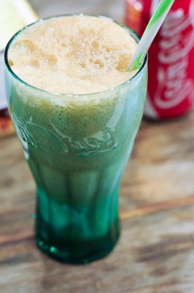 Κλασικό Κόκα-Κόλα με Παγωτό 2 Coke float σε πράσινο ποτήρι Coca-Cola με καλαμάκι και κόκκινο-άσπρο κουτί Coca-Cola στο παρασκήνιο.