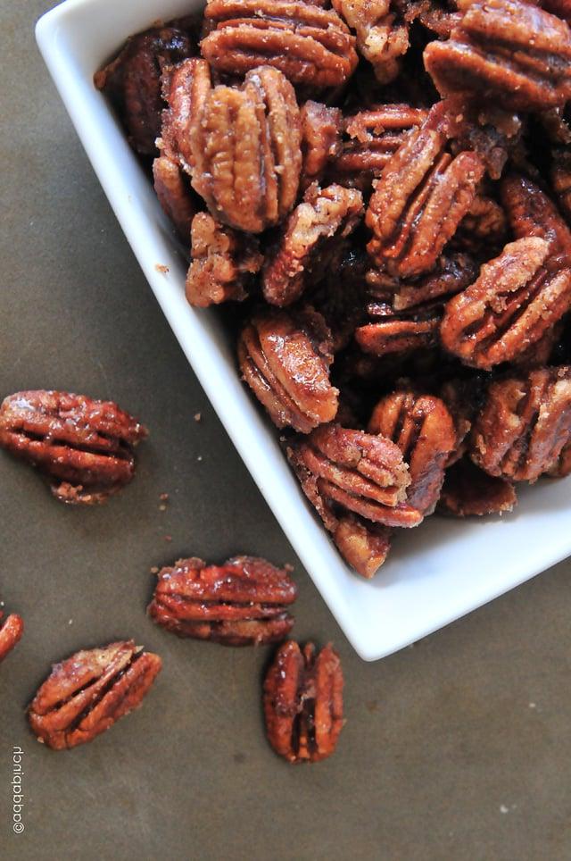 Συνταγή για Κανελάτα Πεκάν 2 Εύκολα pecan με κανέλα σε ένα λευκό μπολ σερβιρίσματος πάνω σε μια επιφάνεια από σκυρόδεμα.