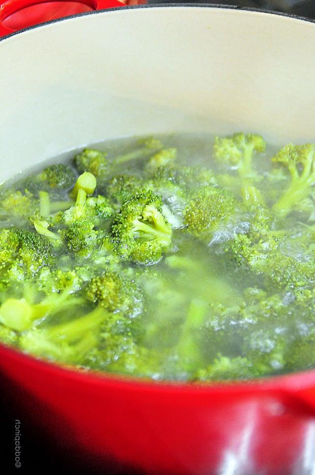 broccoli-boiled-DSC_1455 Κόκκινη κατσαρόλα γεμάτη με ανθοδέσμες μπρόκολου που μαγειρεύονται στην κουζίνα.