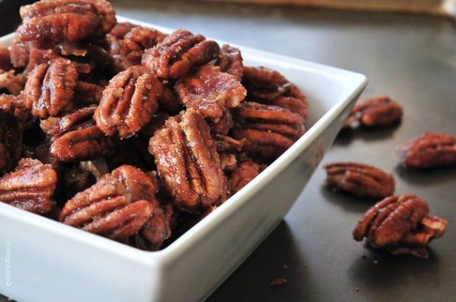 Συνταγή για Κανελάτα Πεκάν 3 Pecan με κανέλα σε ένα λευκό μπολ σερβιρίσματος πάνω σε μια σκούρα επιφάνεια.
