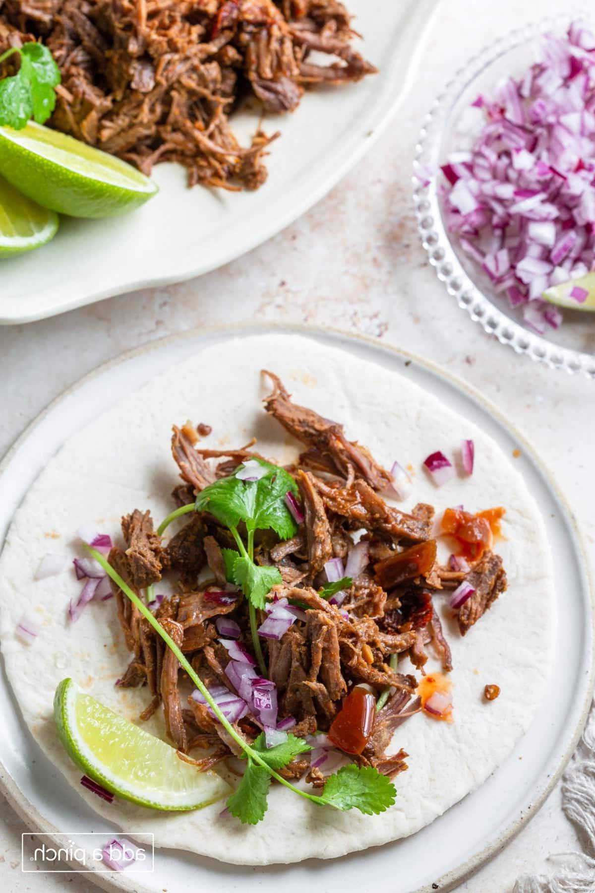 Barbacoa σε μαλακή τορτίγια με λάιμ, κόλιανδρο και κόκκινο κρεμμύδι.