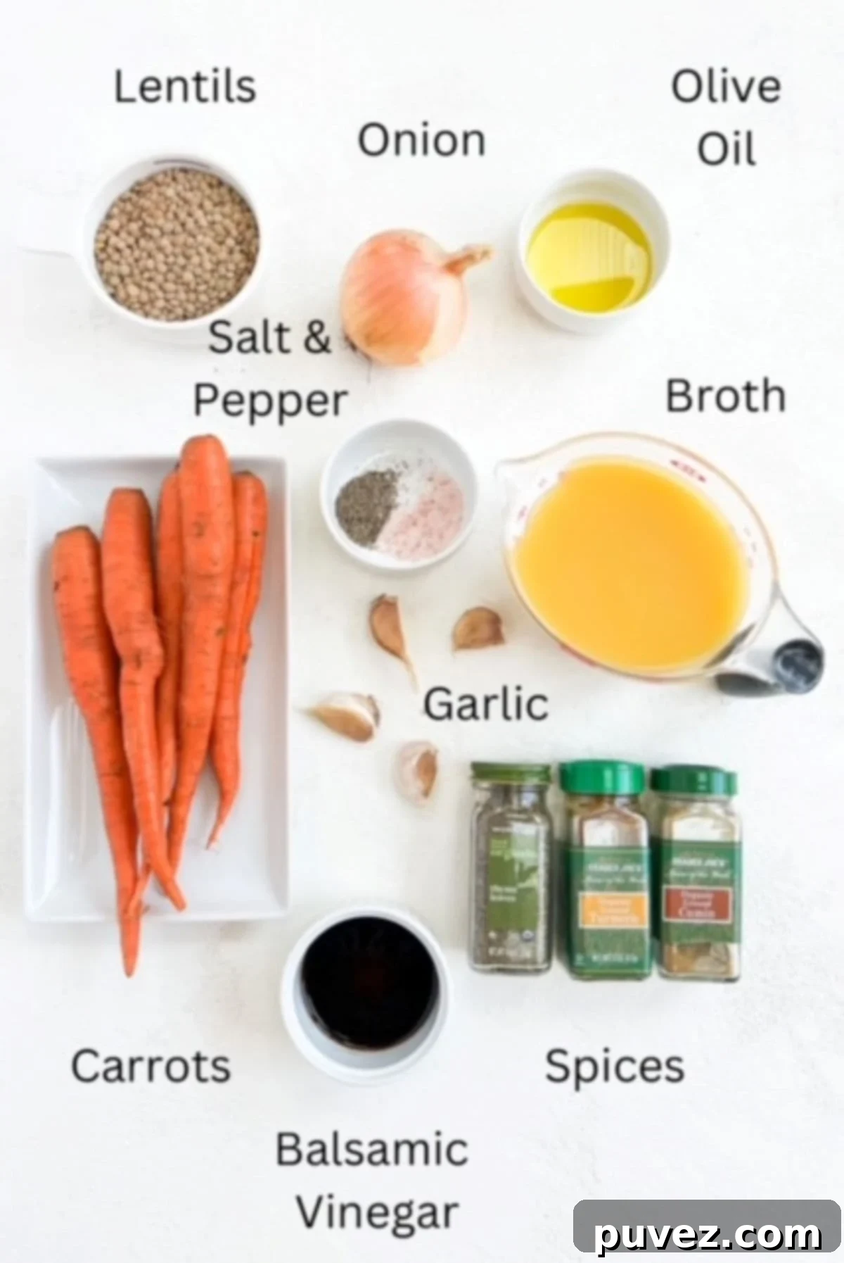 A flat lay photograph showcasing all the fresh and dry ingredients required to make a wholesome Carrot and Lentil Soup, neatly arranged on a white surface.