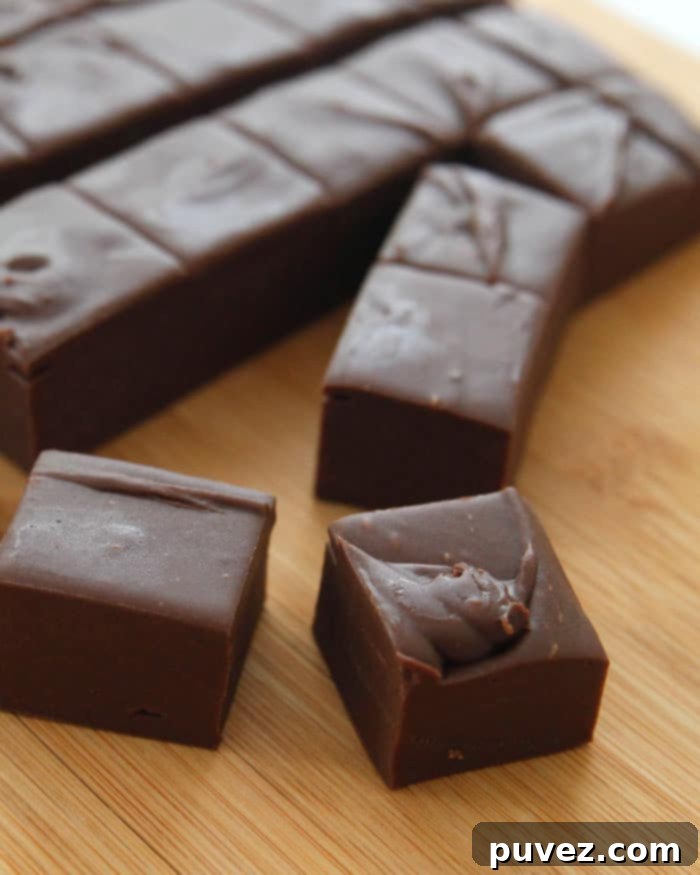 Three minute fudge cut into squares on a wooden board. 2 squares are separated from the rest in the front of the image, inviting a taste.