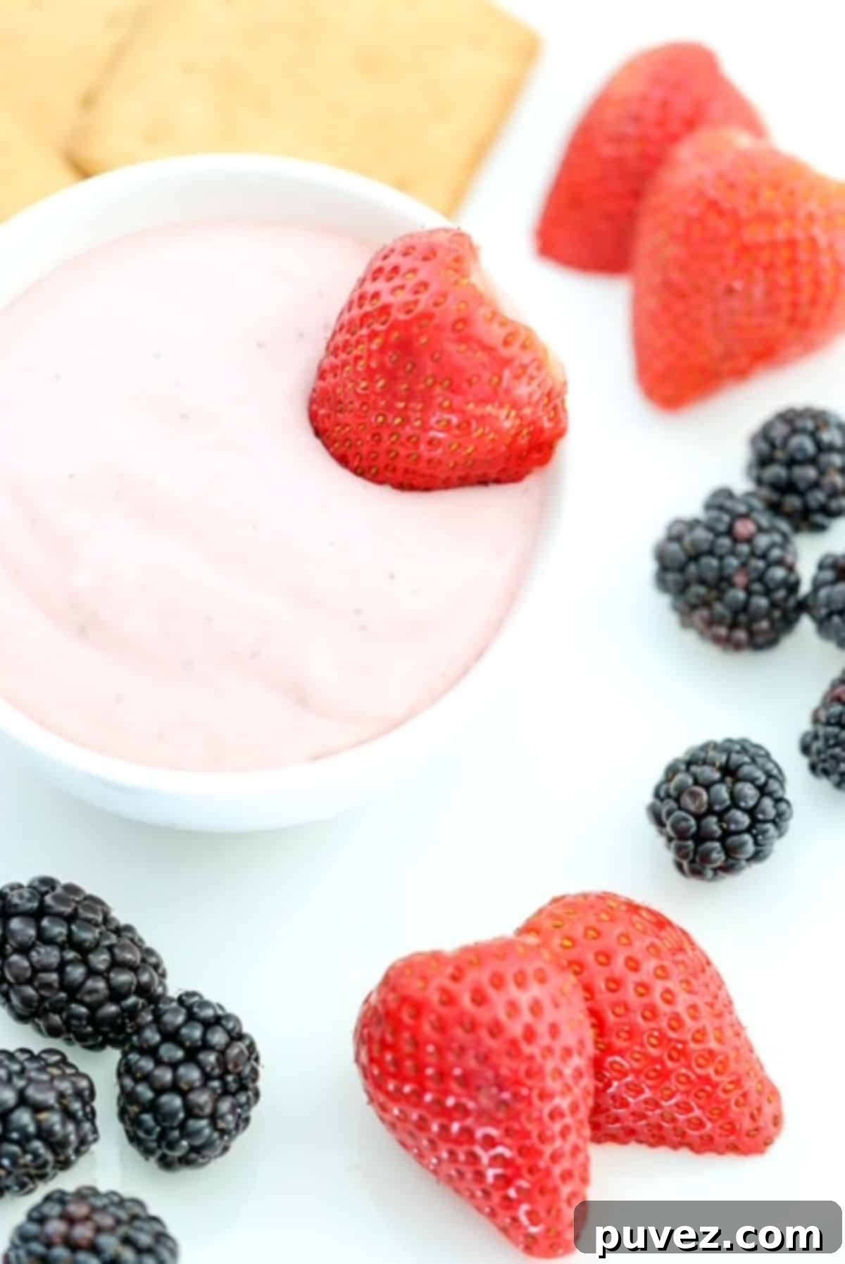 Strawberry fruit dip with berries and graham crackers on a white plate, ready to be enjoyed.