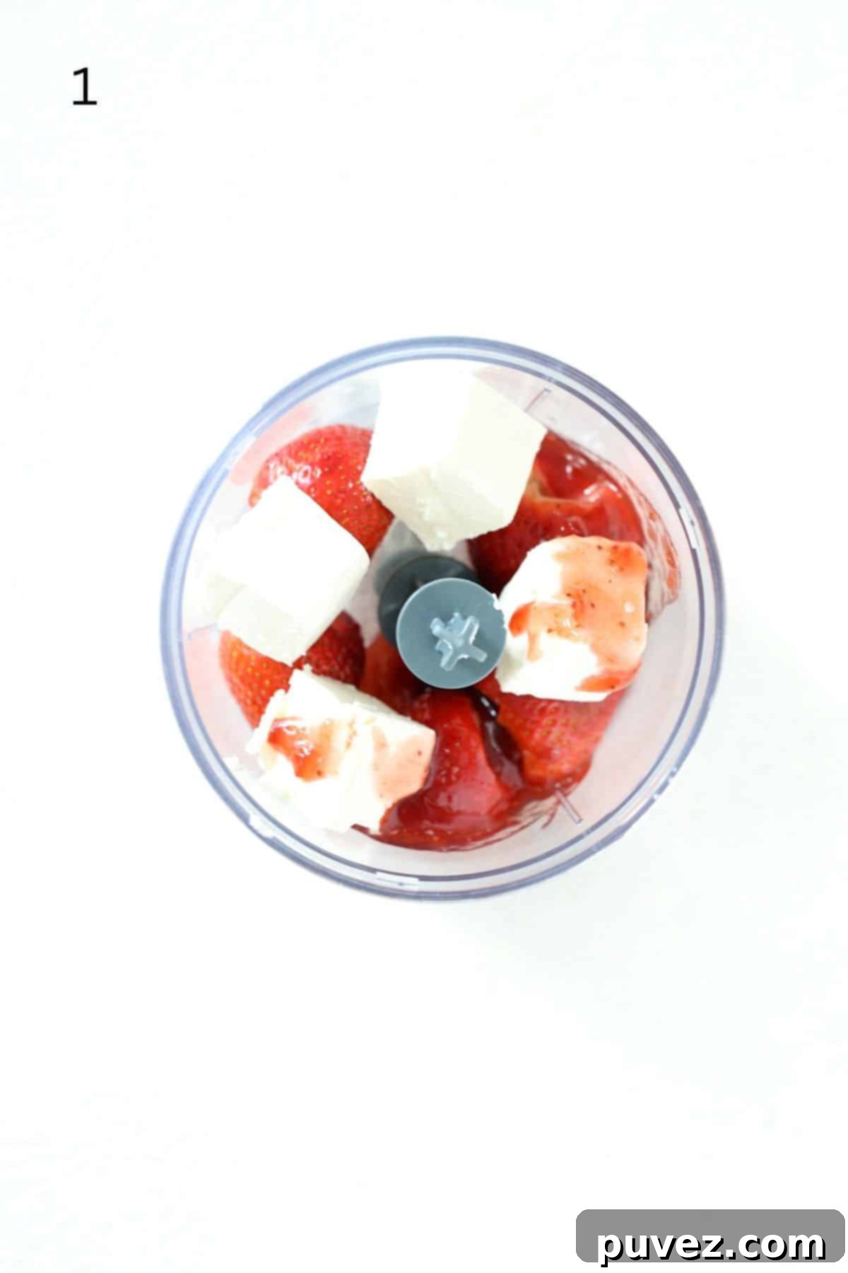 Ingredients for strawberry fruit dip, including cream cheese, strawberries, and fruit spread, placed in a food processor without the lid.