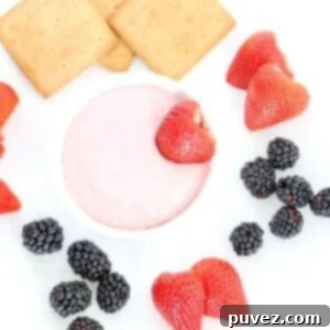 A bowl of creamy strawberry fruit dip, garnished with a fresh strawberry, ready to be served.