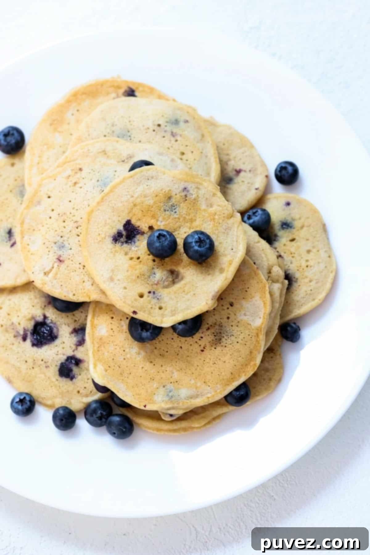 Hearty Whole Wheat Blueberry Bliss 2 A plate of whole wheat blueberry pancakes topped with fresh blueberries and a drizzle of maple syrup.