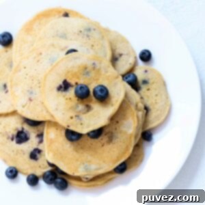 Hearty Whole Wheat Blueberry Bliss 4 A plate of whole wheat blueberry pancakes topped with fresh blueberries.