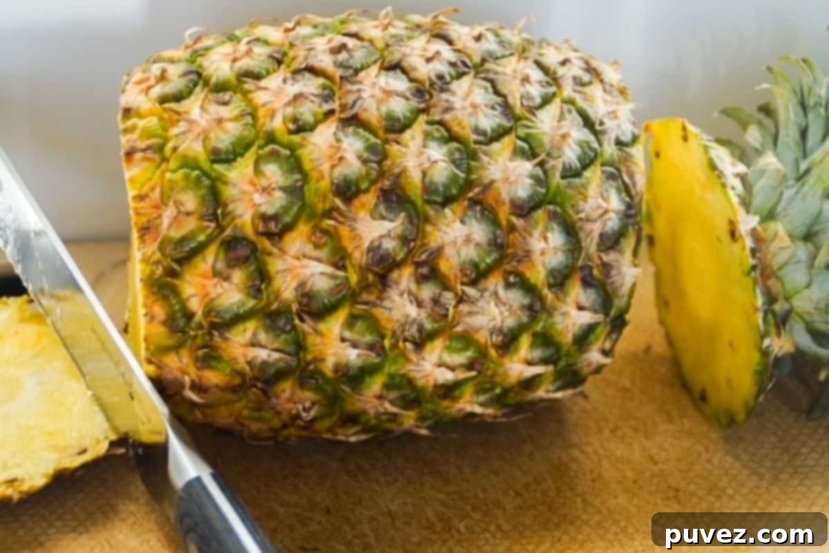 Whole pineapple laying on its side with the ends cut off.