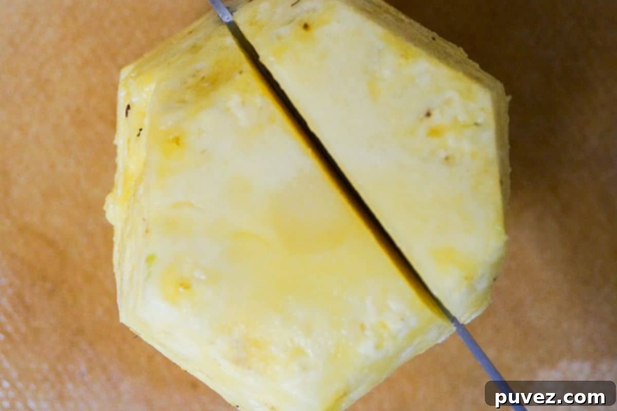Tip view of a peeled pineapple, sliced along the core with a knife.