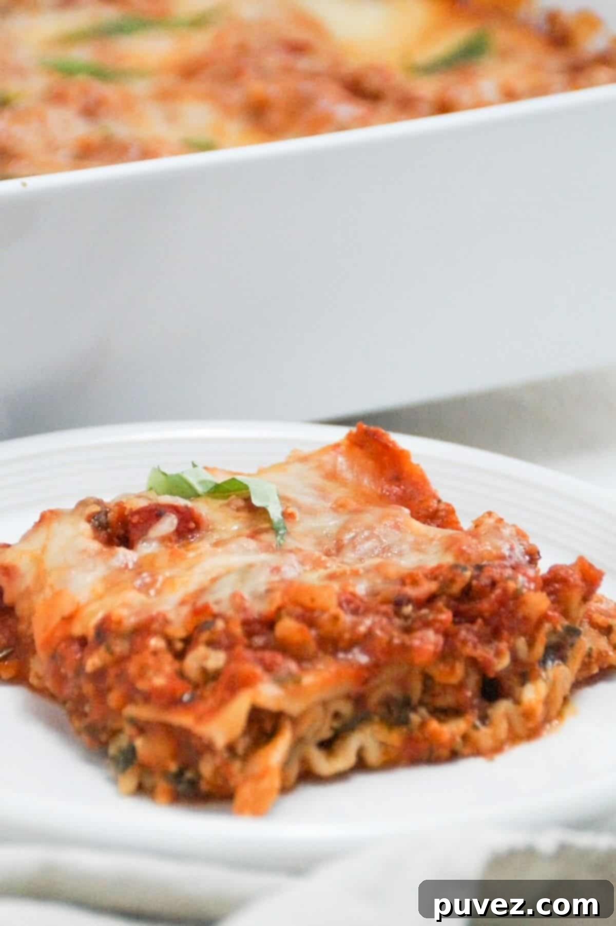 One piece of lasagna on a white plate.
