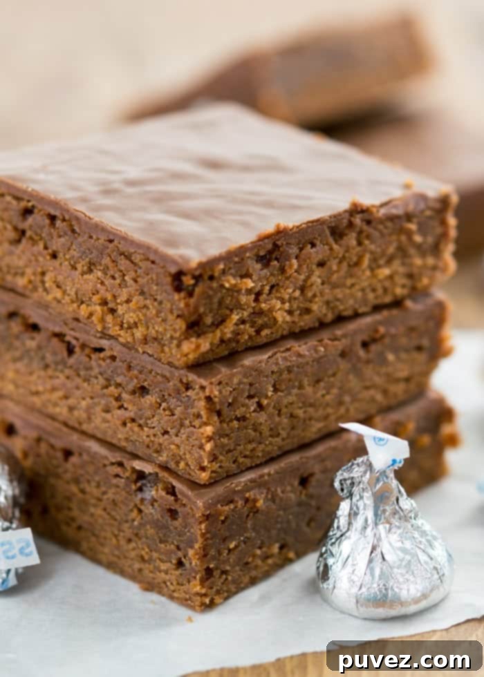 Rich, fudgy Hershey's Kisses brownies stacked high, showing the smooth ganache frosting