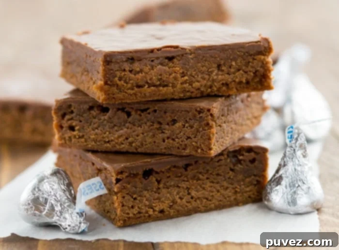 A stack of fudgy Hershey's Kisses brownies with ganache frosting, ready to be served