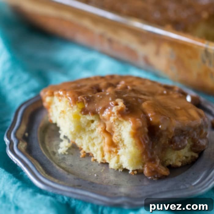 A delicious slice of Salted Caramel Butterscotch Poke Cake, topped with creamy frosting and a sprinkle of sea salt.
