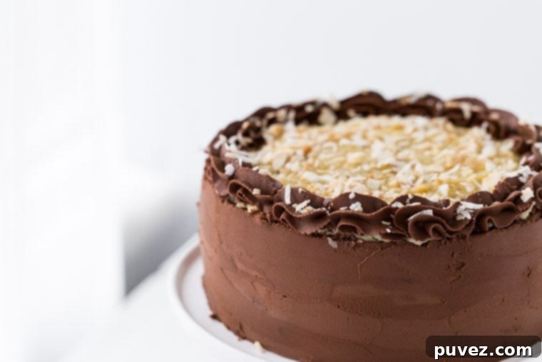 This German Chocolate Cake is four layers of moist chocolate cake soaked in rum syrup and filled with sweet coconut custard filling and wrapped beautifully in a chocolate ganache frosting.