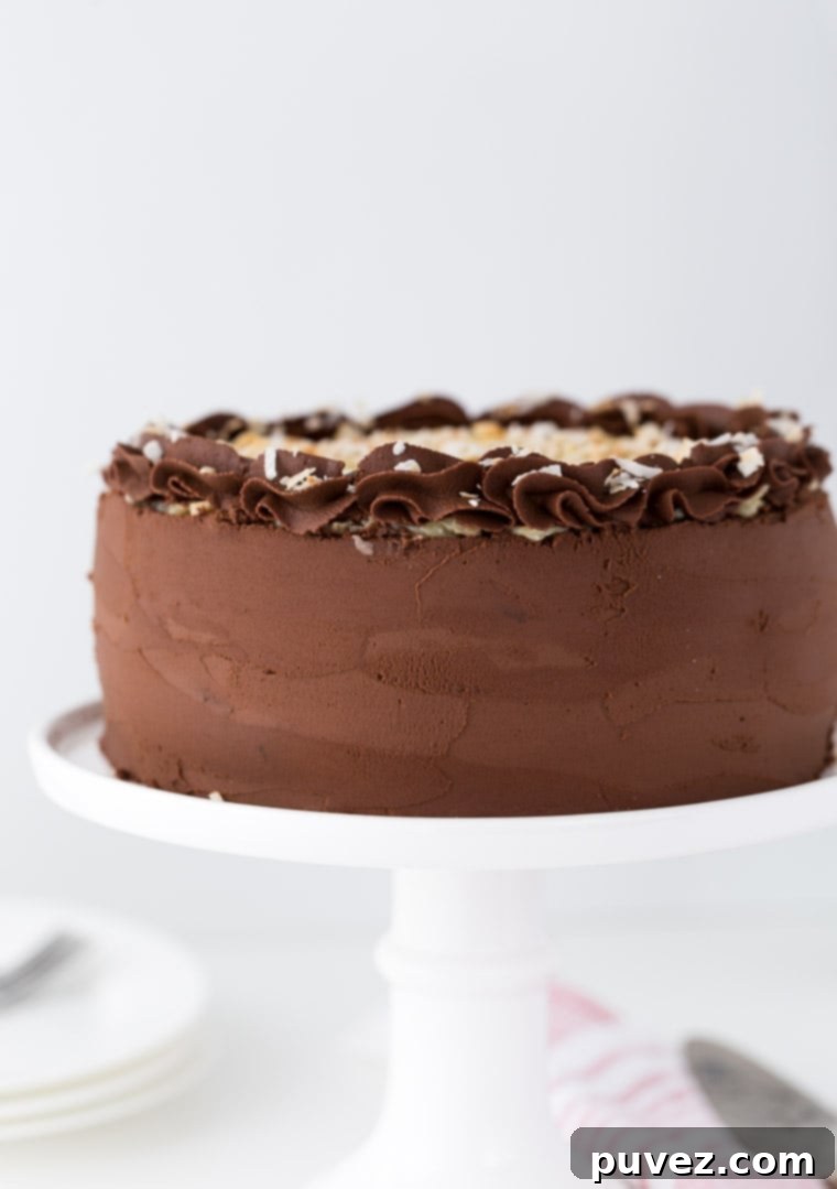 This German Chocolate Cake is four layers of moist chocolate cake soaked in rum syrup and filled with sweet coconut custard filling and wrapped beautifully in a chocolate ganache frosting.