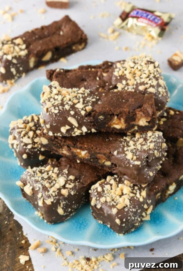 Chocolate Dipped Snickers Cookie Bars arranged on parchment paper