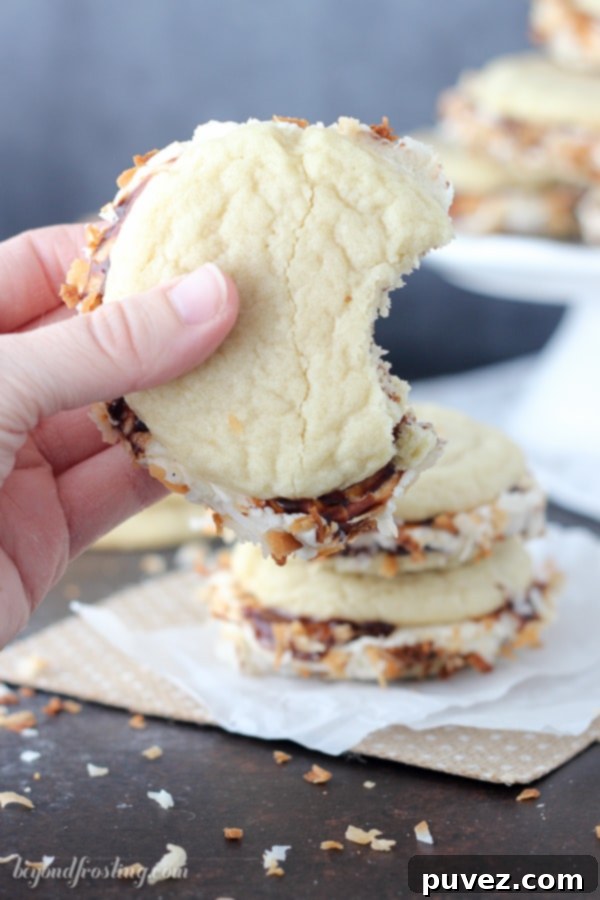 A stack of homemade Samoa Cookie Sandwiches, showcasing the toasted coconut rim and the delightful gooey layers inside