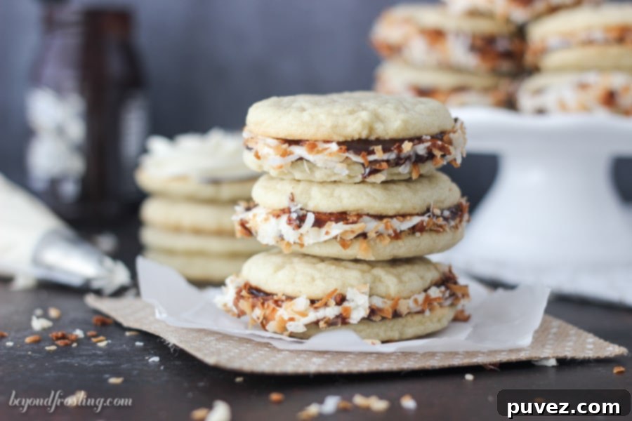 Mouthwatering Samoa Cookie Sandwich cut in half, revealing the soft cookie texture, creamy caramel, and hot fudge layers, topped with toasted coconut