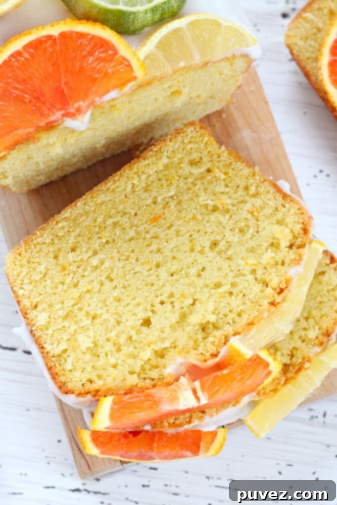 A close-up of a slice of citrus lemon bread recipe, showing its moist texture and the vibrant yellow color from the citrus. Garnish with fresh lemon slices.