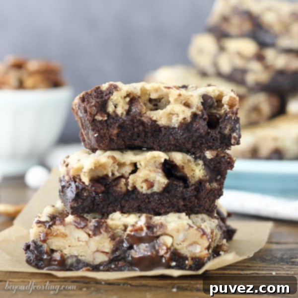 A close-up of Mississippi Mud Brookies, showcasing the distinct layers of fudgy chocolate brownies beneath soft, chewy chocolate chip cookies. Generously loaded with crunchy pecans and pockets of gooey marshmallows, this treat promises indulgence in every bite.