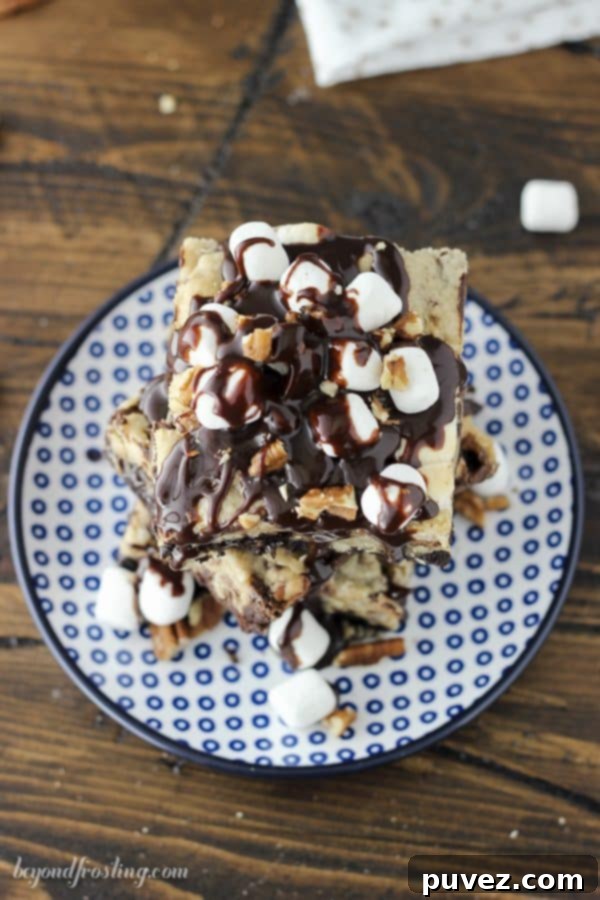 The initial stage of preparing Mississippi Mud Brookies: Spreading the rich chocolate brownie batter evenly in a parchment-lined pan, forming the fudgy base. It's ready for the next delicious layer of cookie dough, pecans, and marshmallows.