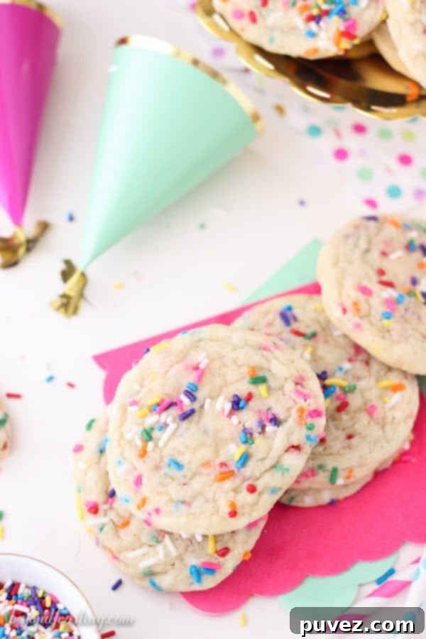 Close-up of freshly baked sprinkle sugar cookies on a baking sheet, showcasing their soft texture and colorful sprinkles.