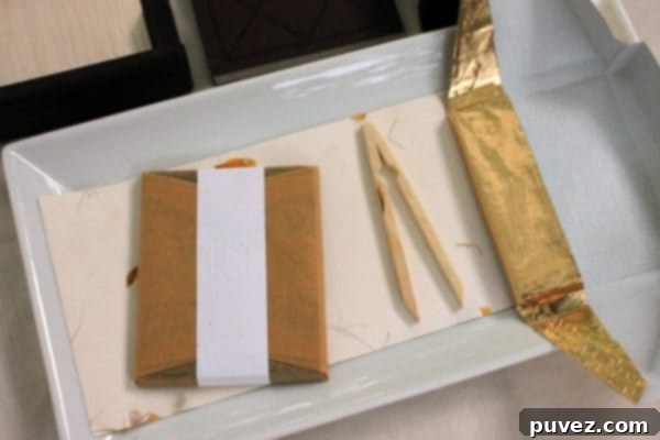 A hand carefully unwrapping a To'ak chocolate bar from its elegant packaging
