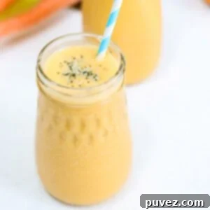 One Carrot Banana Smoothie in a glass jar with a blue and white striped straw.