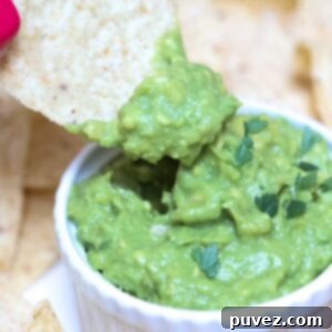 A chip being dipped into creamy, fresh 4-ingredient guacamole served in a white ramekin, emphasizing its delicious appeal.