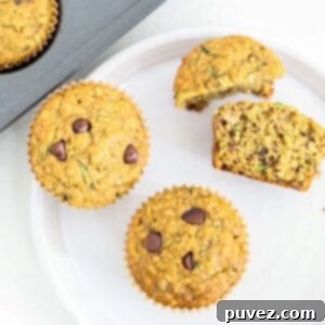 Two whole and two half banana zucchini chocolate chip muffins on a white plate.