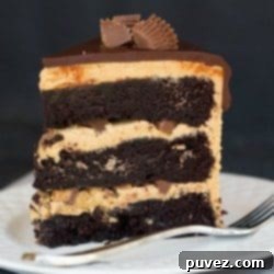 Peanut Butter Cup Overload Cake, a rich dessert with layers of cake and frosting, topped with many peanut butter cups.