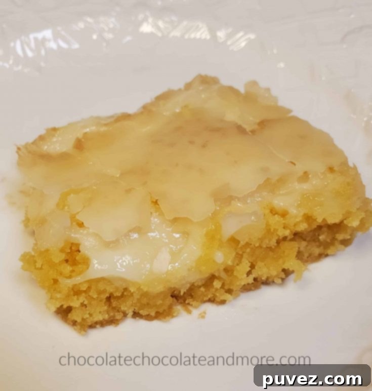 A gooey cream cheese bar on a white plate, ready to be enjoyed.