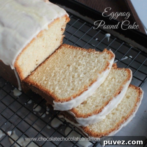 A slice of golden brown Eggnog Pound Cake topped with a light glaze and a dusting of nutmeg, served on a white plate.