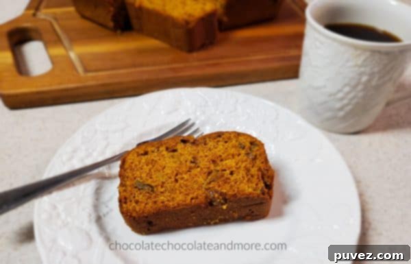Enjoying a slice of homemade Pumpkin Raisin Bread with a steaming cup of coffee, showcasing a cozy breakfast or snack moment. A sliced loaf sits on a wooden board.