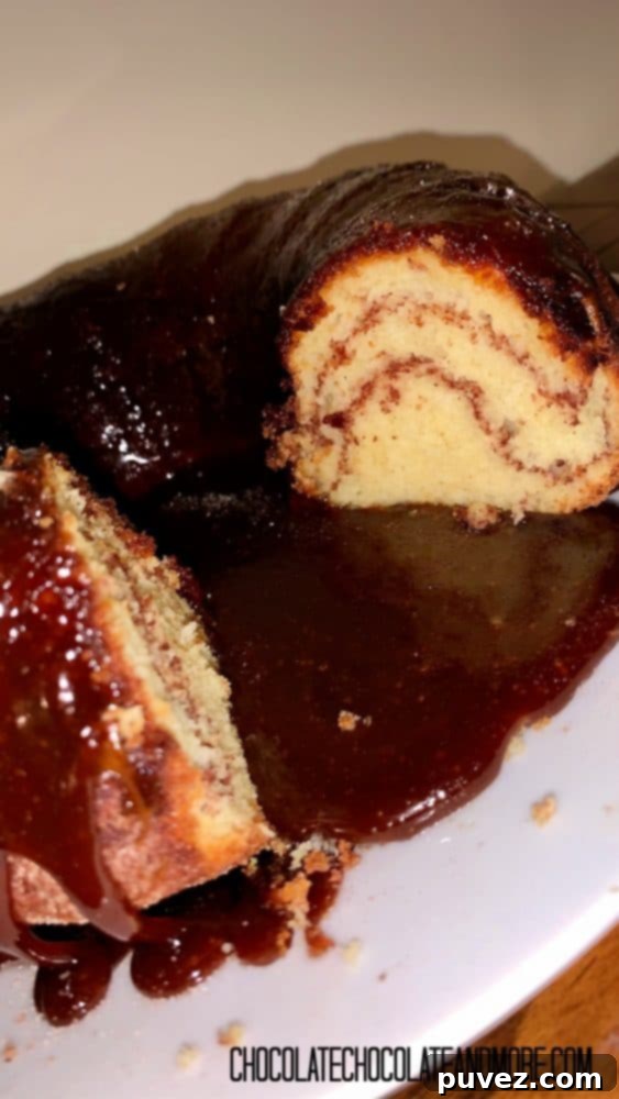 Two generous slices of Monkey Bread Cake have been cut from the main bundt cake, revealing the beautiful cinnamon swirls within. The cake, sitting on a white plate against a wooden table, promises a delightful treat.