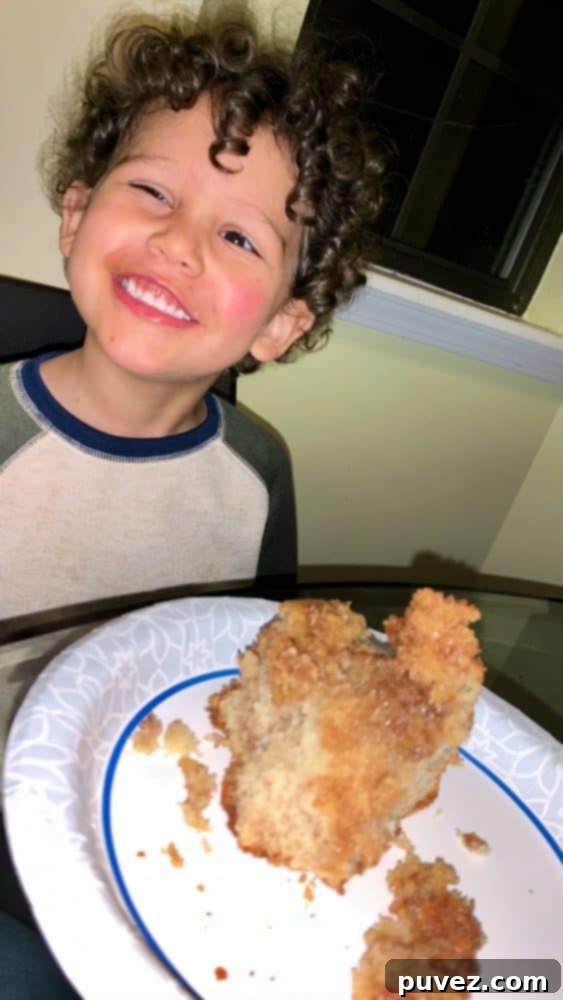 A young boy, Edward, happily enjoys a slice of Monkey Bread Cake, his face alight with joy as he savors the sweet, caramelized treat. The image captures the pure delight of indulging in a homemade dessert.