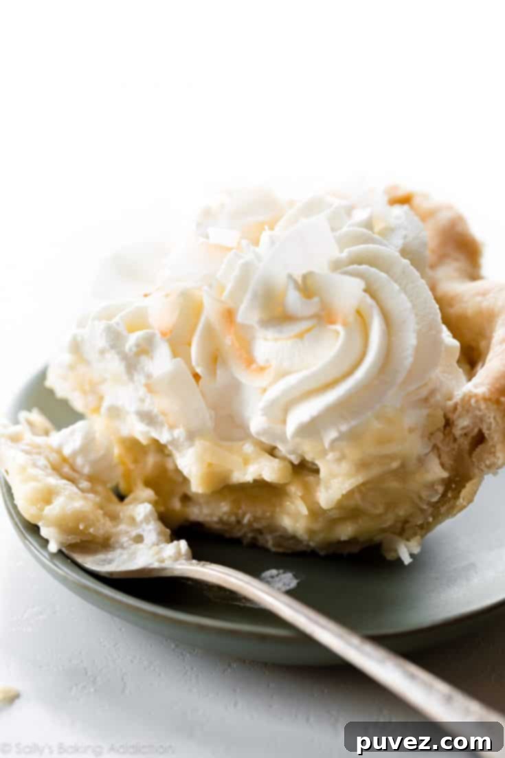 Rich and creamy Homemade Coconut Cream Pie, topped with whipped cream.