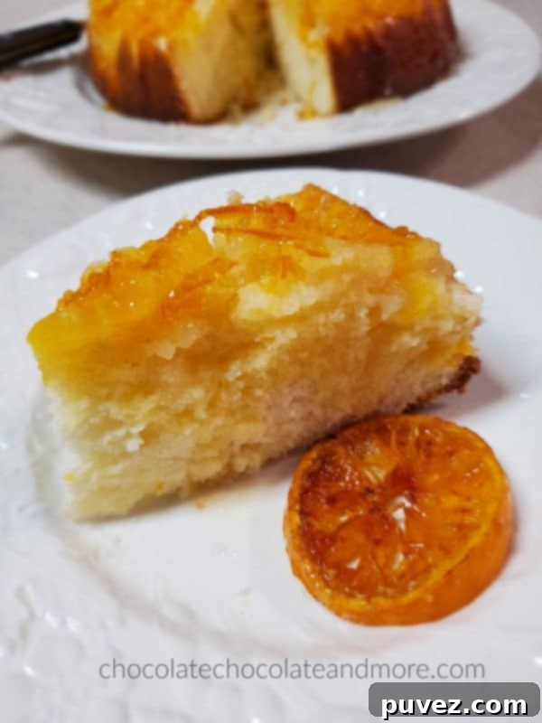 a slice of mandarin upside down cake on a plate with a slice of candied orange