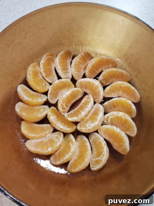a glass dish carefully lined with individual sections of mandarin oranges in a decorative pattern