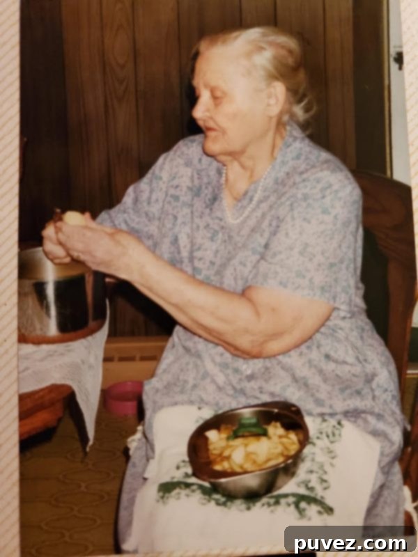 A close-up shot showing hands expertly peeling apples, highlighting the traditional, hands-on method Gram used to prepare her famous apple pie.