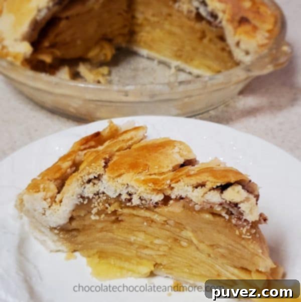 A perfectly baked apple pie, partially sliced, showing the delicate, flaky texture of the crust and the abundant apple filling inside.