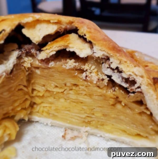 A beautifully sliced apple pie on a plate, revealing abundant layers of thinly sliced apples cooked down to a tender, juicy perfection.