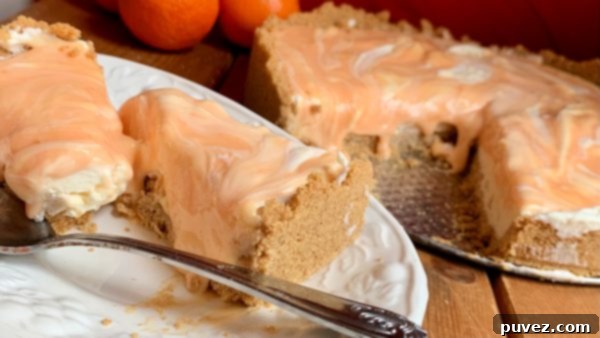 Two slices of Orange Creamsicle Swirl Cheesecake and the rest of the cheesecake sitting in front of a vibrant red background, showcasing its beautiful layers.