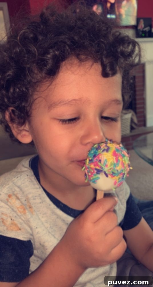 A child's hands eagerly reaching for an Easter Egg Cake Pop in a mini cupcake holder, signifying a successful, kid-approved treat.