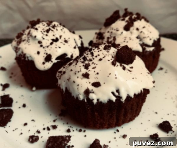 Three Frosted Oreo Brownie Cups sitting on a white plate in front of a white background.