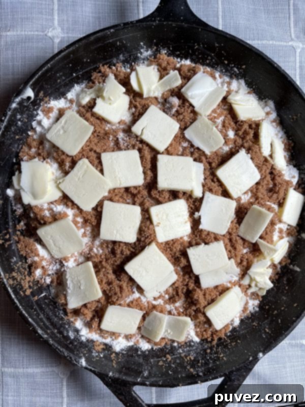 Thin, even slices of butter spread across the top layer of dry cake mix and crumb topping in the baking dish.