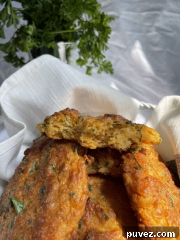 Copycat Red Lobster Cheddar Bay Biscuits remake in front of a white background and a jar of parsley, showcasing the golden-brown biscuits.