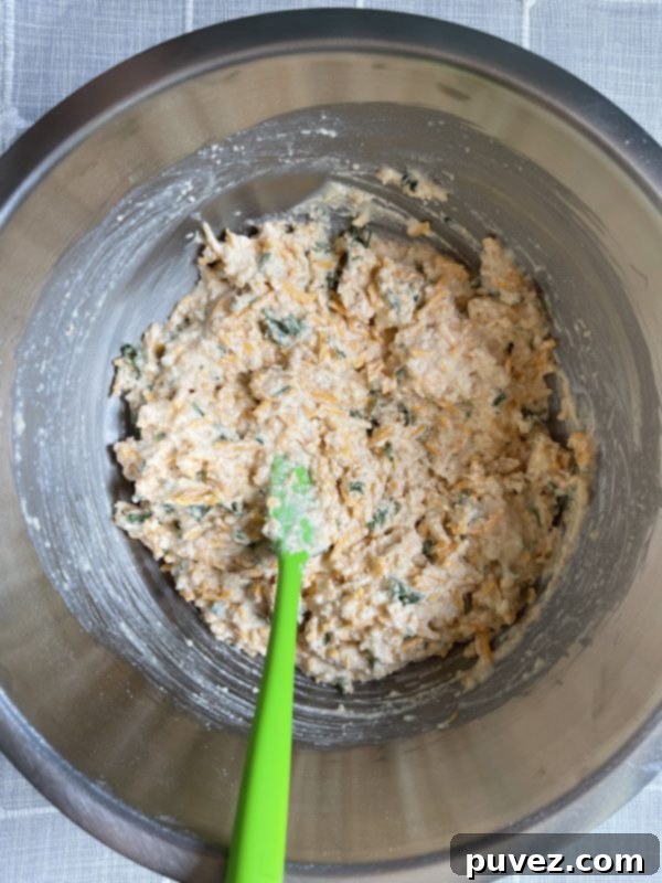 Copycat Red Lobster Cheddar Bay Biscuits batter, showing cheese, parsley, and milk mixed into the dry ingredients.