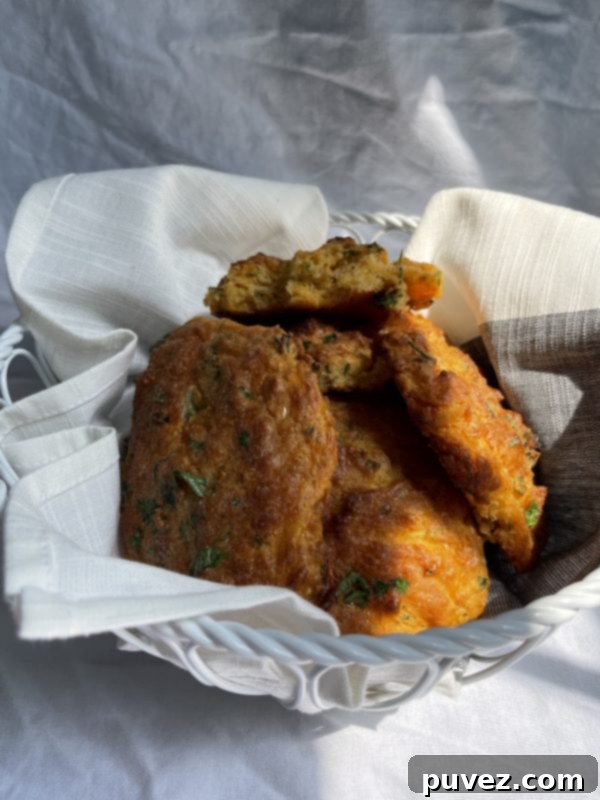 Freshly baked Copycat Red Lobster Cheddar Bay Biscuits remake in a woven basket in front of a white background, glazed with garlic butter.